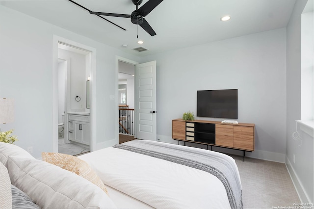 bedroom featuring light colored carpet, ensuite bath, and ceiling fan