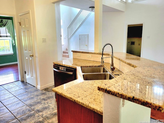 kitchen with dishwasher, kitchen peninsula, sink, and light stone countertops