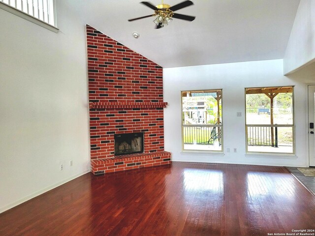 unfurnished living room with high vaulted ceiling, ceiling fan, a brick fireplace, and dark hardwood / wood-style flooring