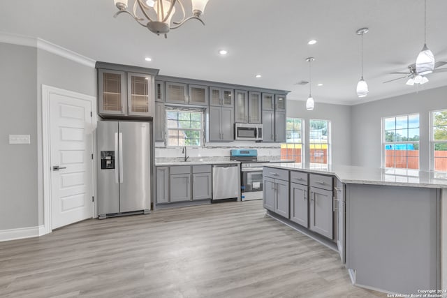 kitchen with ceiling fan with notable chandelier, appliances with stainless steel finishes, a healthy amount of sunlight, and hardwood / wood-style floors