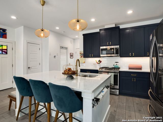 kitchen featuring a breakfast bar area, a center island with sink, light hardwood / wood-style flooring, appliances with stainless steel finishes, and decorative backsplash