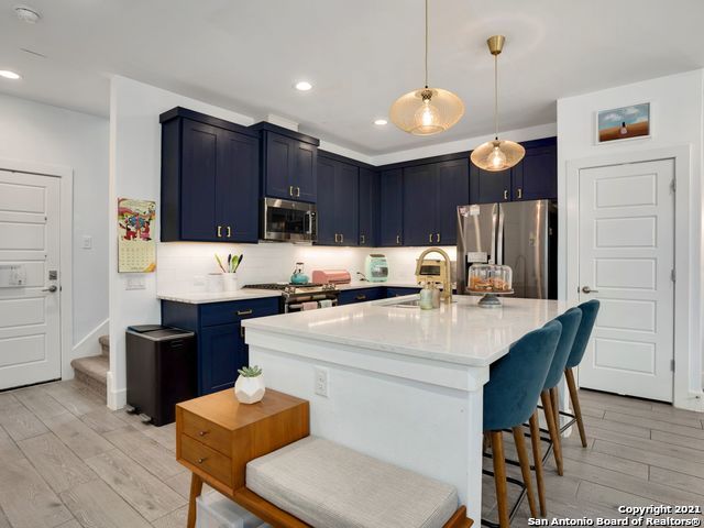 kitchen featuring blue cabinetry, stainless steel appliances, an island with sink, a breakfast bar, and light hardwood / wood-style floors