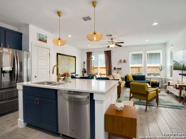 kitchen with light hardwood / wood-style flooring, decorative light fixtures, stainless steel appliances, blue cabinets, and a kitchen island with sink