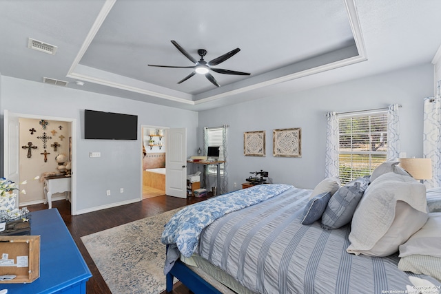 bedroom with dark wood-type flooring, ceiling fan, connected bathroom, and a raised ceiling