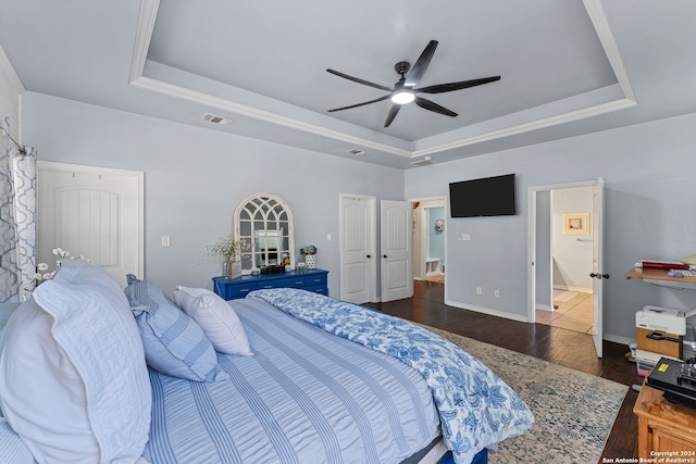 bedroom with a tray ceiling, ceiling fan, and dark hardwood / wood-style floors