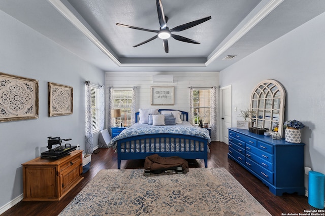 bedroom with a textured ceiling, dark hardwood / wood-style floors, a tray ceiling, a wall mounted air conditioner, and ceiling fan