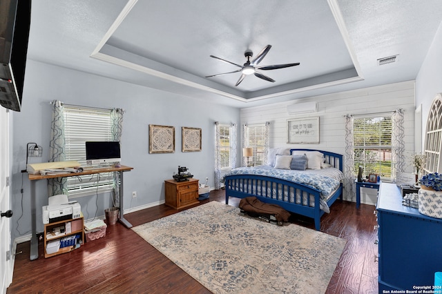 bedroom featuring a textured ceiling, dark wood-type flooring, ceiling fan, and a tray ceiling