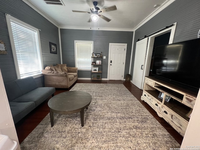 living room with crown molding, ceiling fan, a barn door, and dark hardwood / wood-style flooring