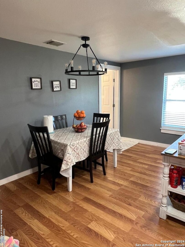 dining space with hardwood / wood-style floors, a notable chandelier, and a textured ceiling