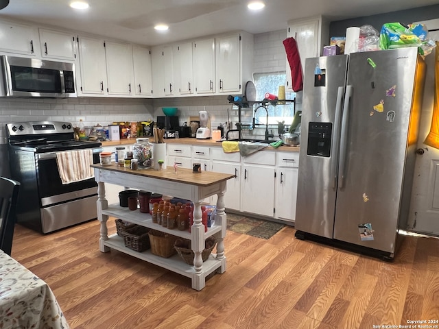 kitchen with stainless steel appliances, light hardwood / wood-style floors, white cabinetry, and sink