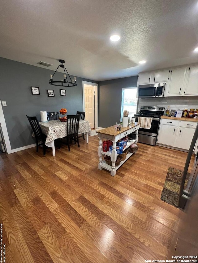 kitchen featuring a notable chandelier, white cabinetry, light hardwood / wood-style flooring, stainless steel appliances, and wood counters