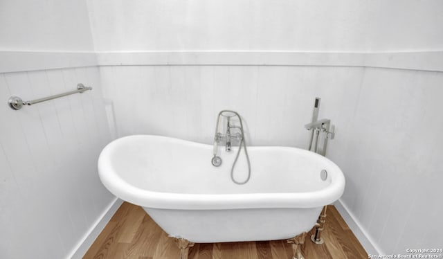 bathroom with hardwood / wood-style flooring and a washtub