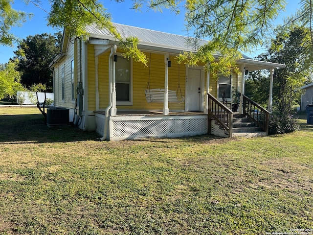 view of front facade with a porch, a front lawn, and central air condition unit