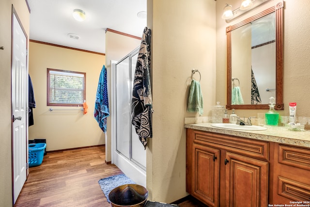 bathroom with vanity, ornamental molding, hardwood / wood-style floors, and an enclosed shower