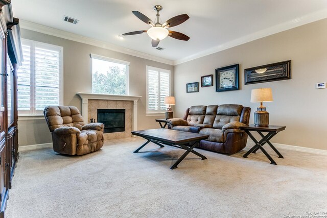 living room featuring ceiling fan, ornamental molding, light carpet, and a tile fireplace