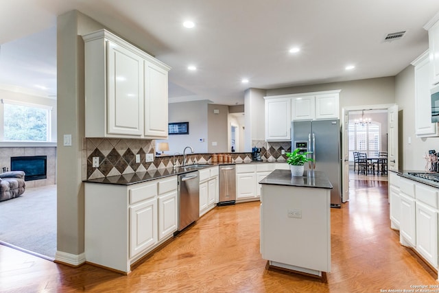 kitchen with a kitchen island, a sink, visible vents, appliances with stainless steel finishes, and dark countertops