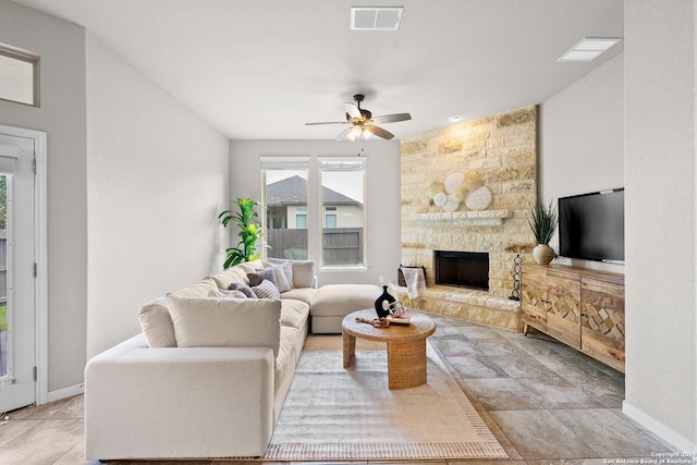 living room with visible vents, a stone fireplace, a ceiling fan, and baseboards
