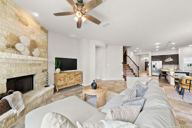 living area featuring a stone fireplace, recessed lighting, stairway, visible vents, and ceiling fan