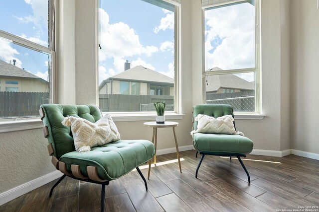 sitting room with wood finished floors, a textured wall, baseboards, and a wealth of natural light