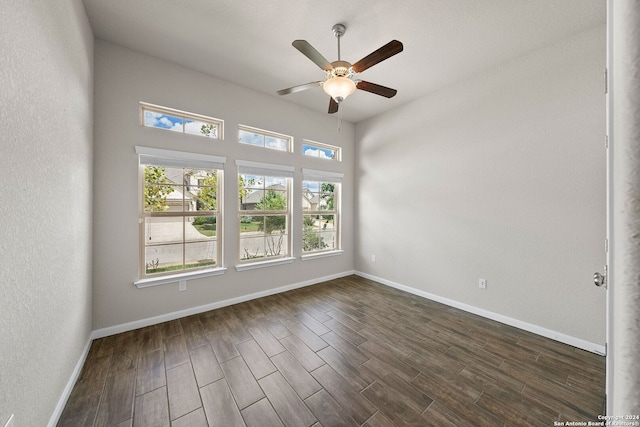unfurnished room featuring a textured wall, ceiling fan, baseboards, and dark wood finished floors