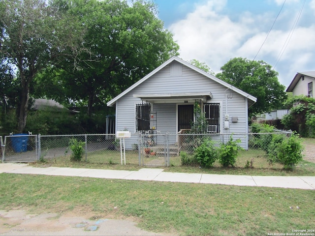 bungalow featuring a fenced front yard, a gate, covered porch, and a front lawn