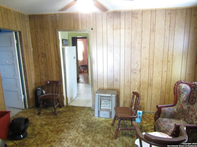 sitting room featuring carpet flooring, ceiling fan, and wood walls