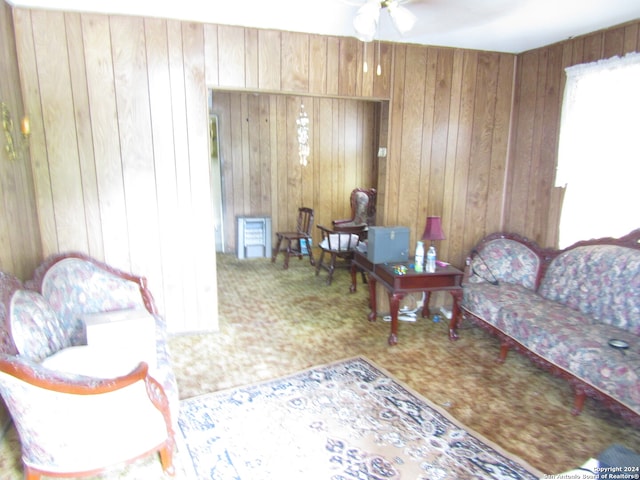 living room with ceiling fan and wood walls