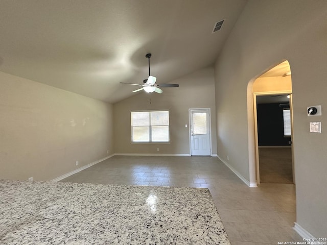 interior space featuring arched walkways, visible vents, light tile patterned flooring, ceiling fan, and baseboards