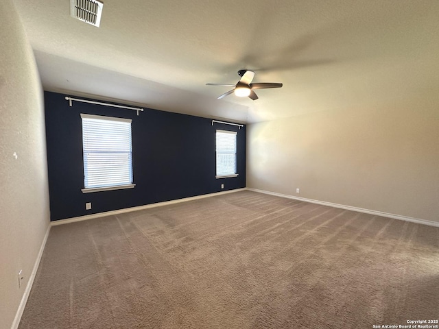 carpeted empty room featuring baseboards, visible vents, and a ceiling fan