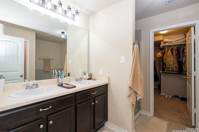 bathroom with a sink, a spacious closet, baseboards, and double vanity