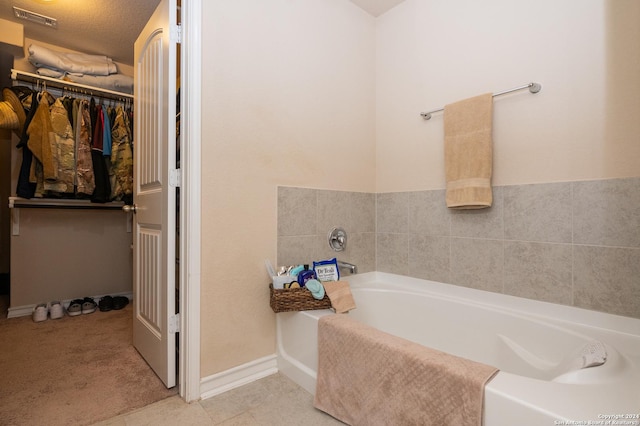 bathroom featuring a garden tub, a walk in closet, and tile patterned floors