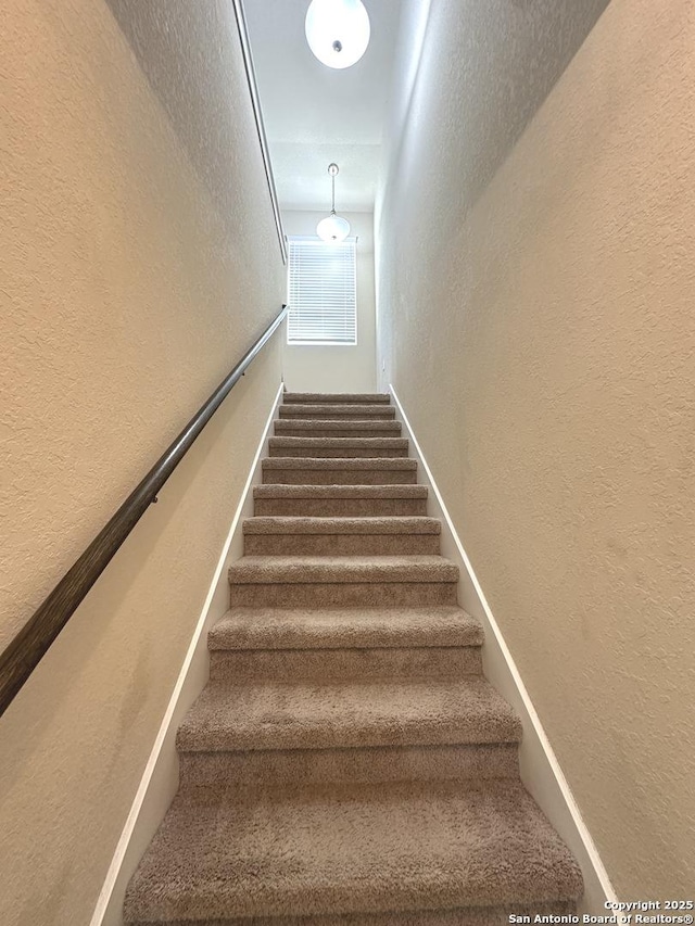 stairway featuring a textured wall