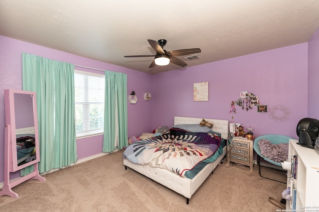 bedroom featuring a textured ceiling, light colored carpet, and ceiling fan