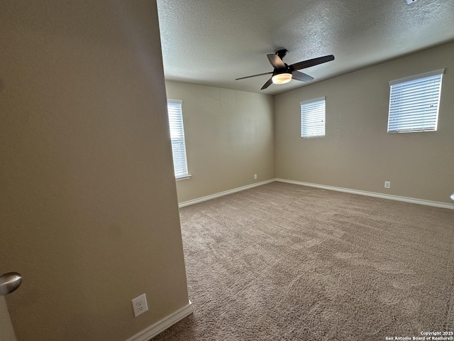 empty room with a textured ceiling, carpet, a ceiling fan, and baseboards