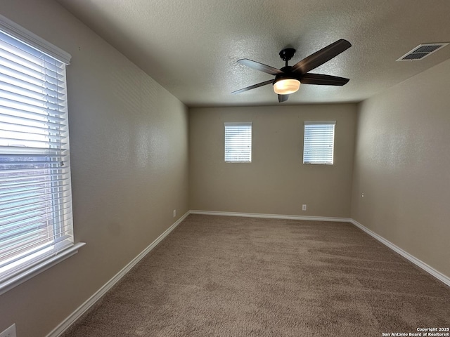 spare room featuring carpet, visible vents, ceiling fan, a textured ceiling, and baseboards