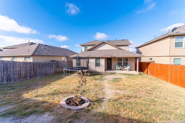 back of property with a trampoline, a lawn, and a patio