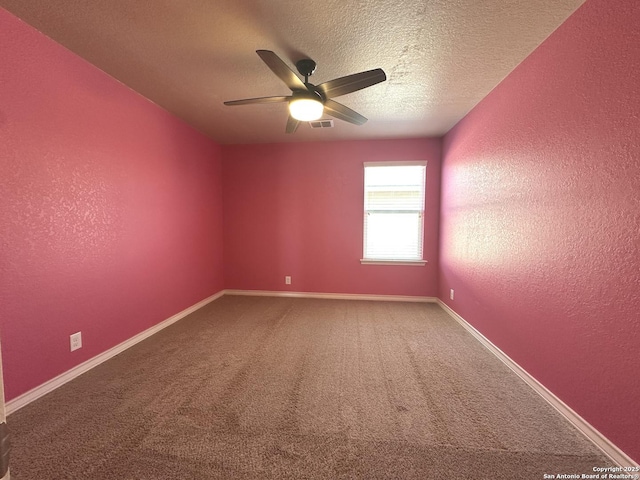 carpeted spare room featuring a textured wall, a textured ceiling, baseboards, and ceiling fan