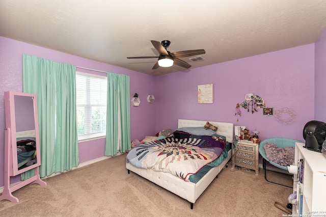 carpeted bedroom featuring a textured ceiling, ceiling fan, and visible vents