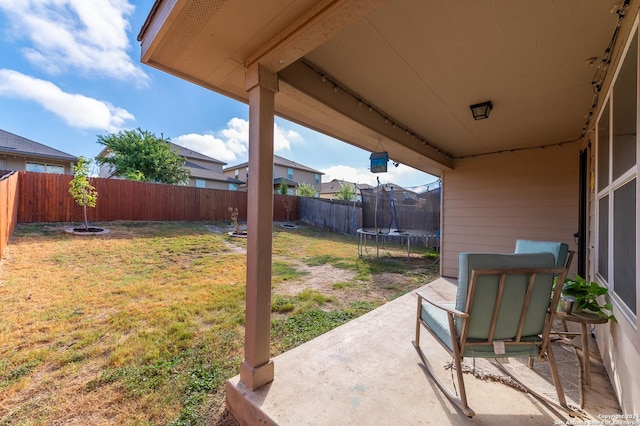 view of yard featuring a trampoline, a patio area, and a fenced backyard