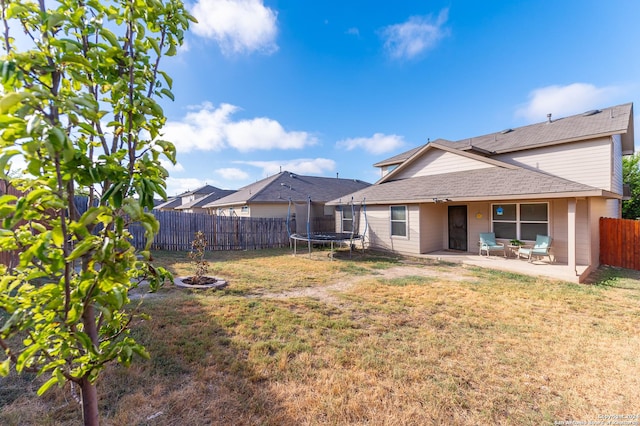 rear view of house with a patio area, a fenced backyard, a trampoline, and a lawn