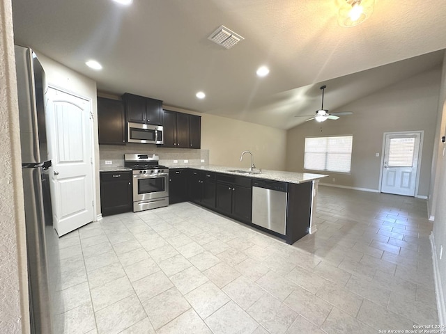 kitchen featuring lofted ceiling, stainless steel appliances, a sink, visible vents, and backsplash