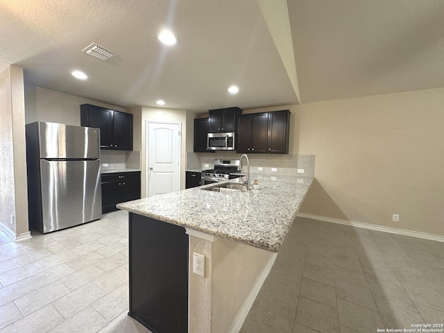 kitchen with a peninsula, visible vents, baseboards, appliances with stainless steel finishes, and backsplash