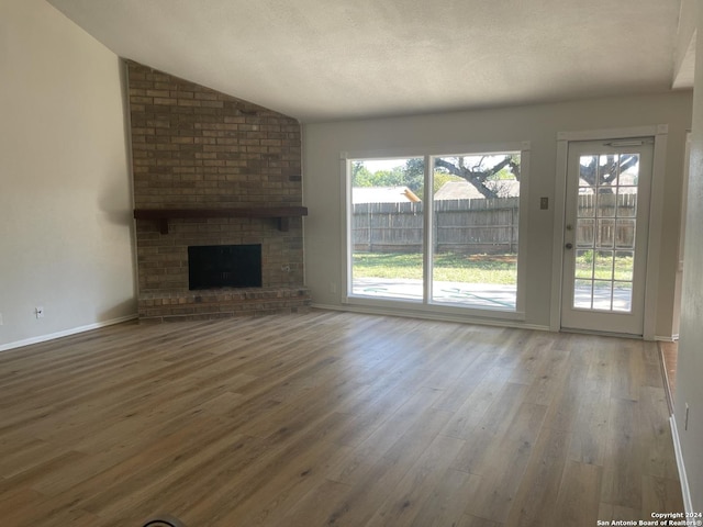 unfurnished living room featuring a healthy amount of sunlight, wood finished floors, and vaulted ceiling