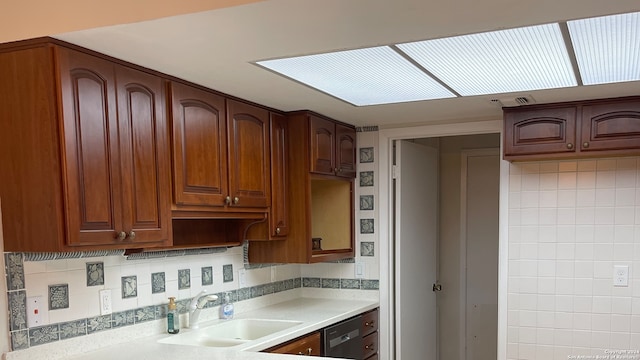 kitchen featuring backsplash, black dishwasher, and sink