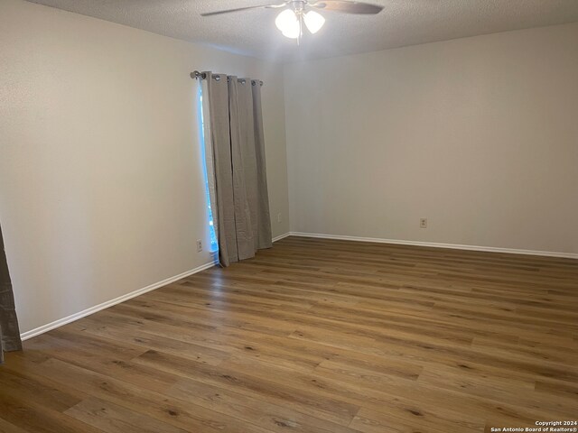 empty room featuring a textured ceiling, ceiling fan, and wood-type flooring