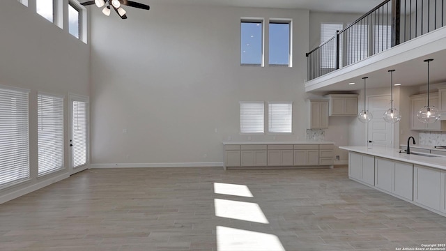 unfurnished living room with ceiling fan, sink, a wealth of natural light, and light hardwood / wood-style floors