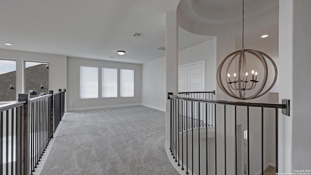 hall with light colored carpet and a chandelier