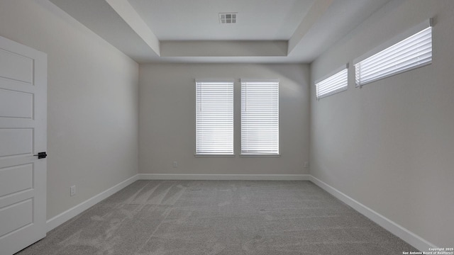 carpeted empty room featuring a tray ceiling