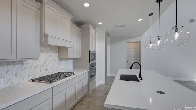 kitchen featuring sink, white cabinetry, pendant lighting, stainless steel appliances, and decorative backsplash