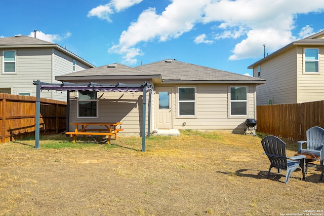 rear view of property featuring a yard and an outdoor fire pit